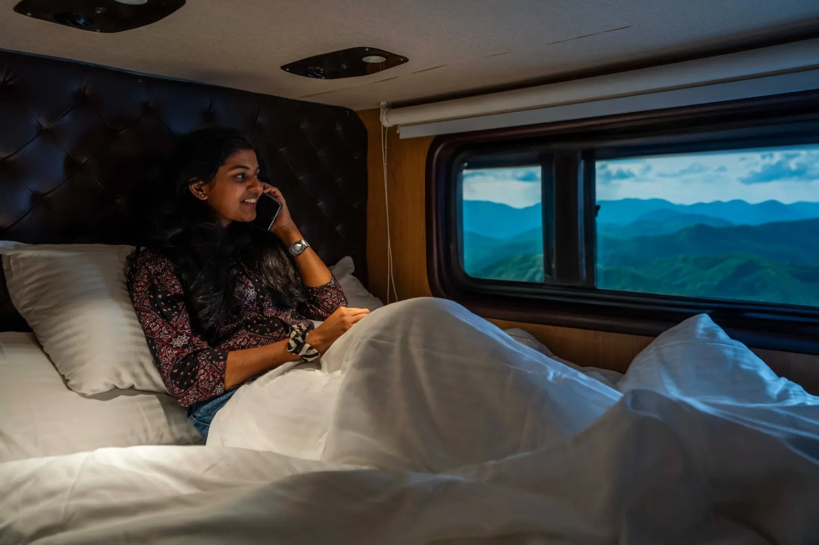 6 seater caravan bedroom in Chennai — guest relaxing on the double bed with a hill view window