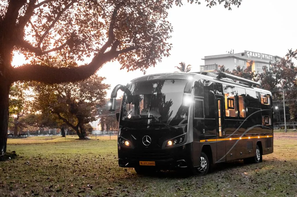 Luxury caravan rental Chennai — caravan rear three-quarter view at night with city lights reflected in dark paint